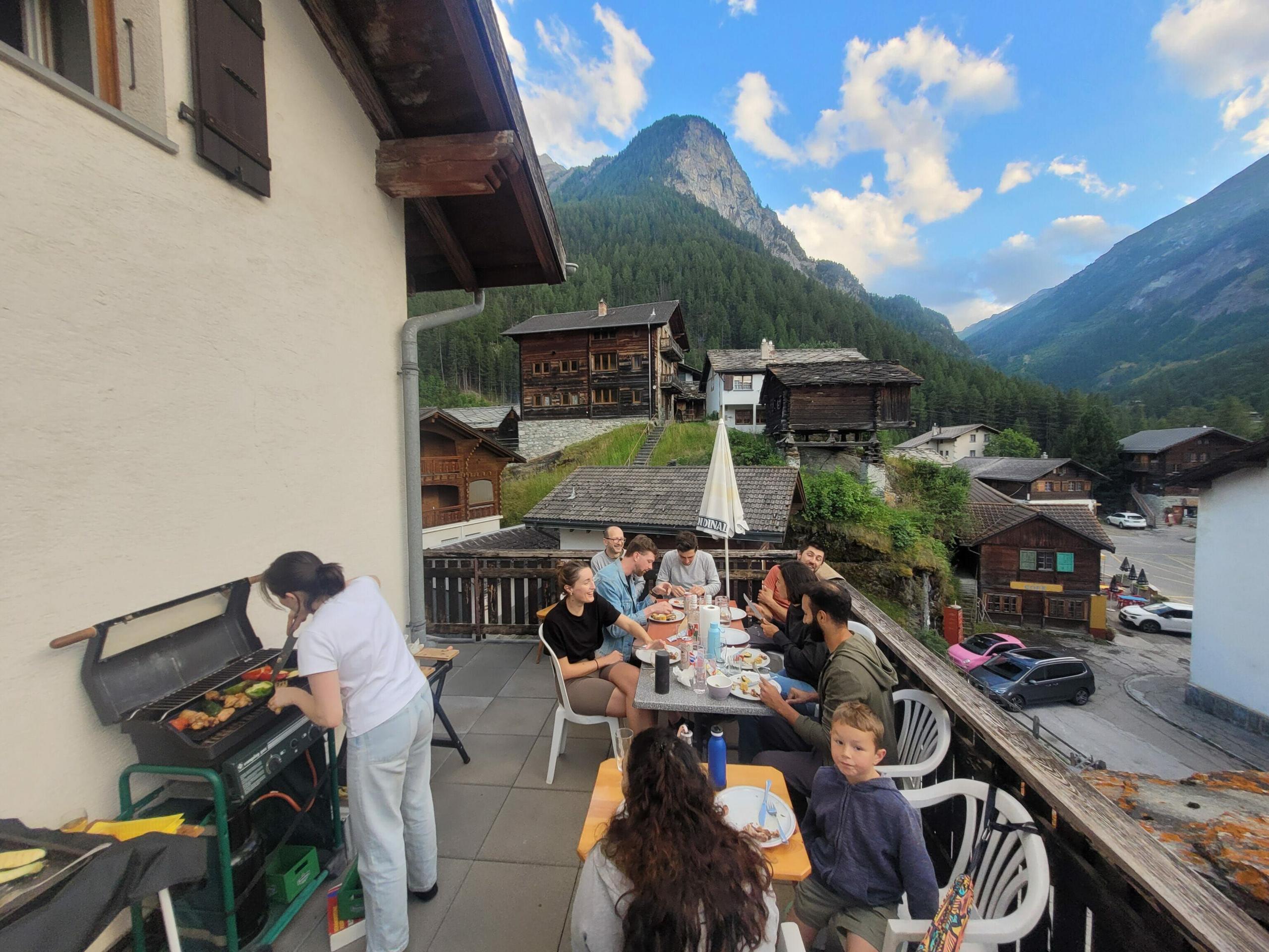 The outdoor entrance area with BBQ and tables at Alpiness coliving.