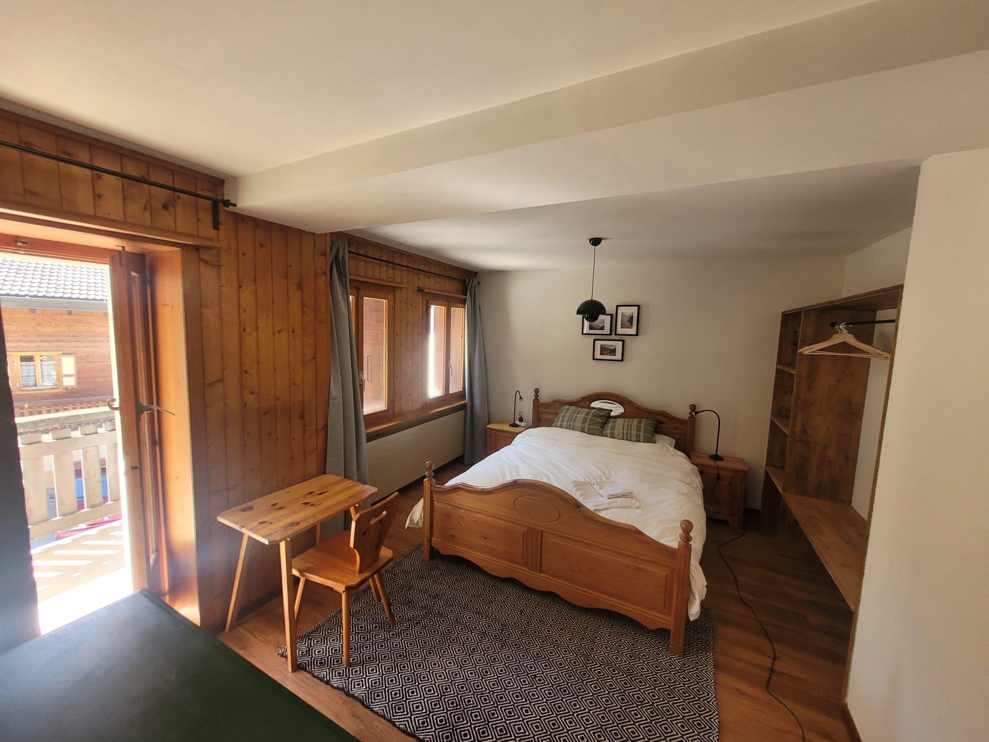 The large double room (17 sqm) with private bathroom at Alpiness coliving, featuring a built-in wardrobe and dresser.