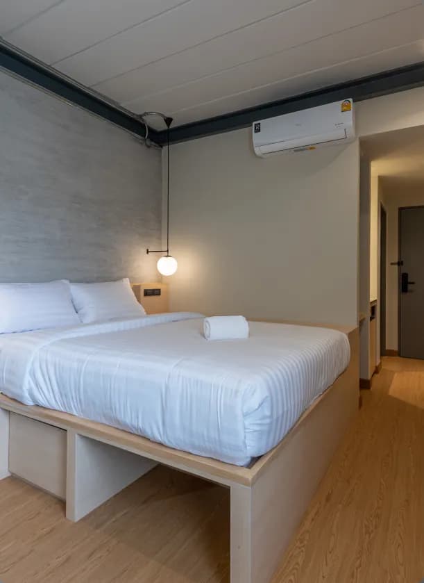 Ensuite room queen bed with globe pendant lights and concrete headboard wall