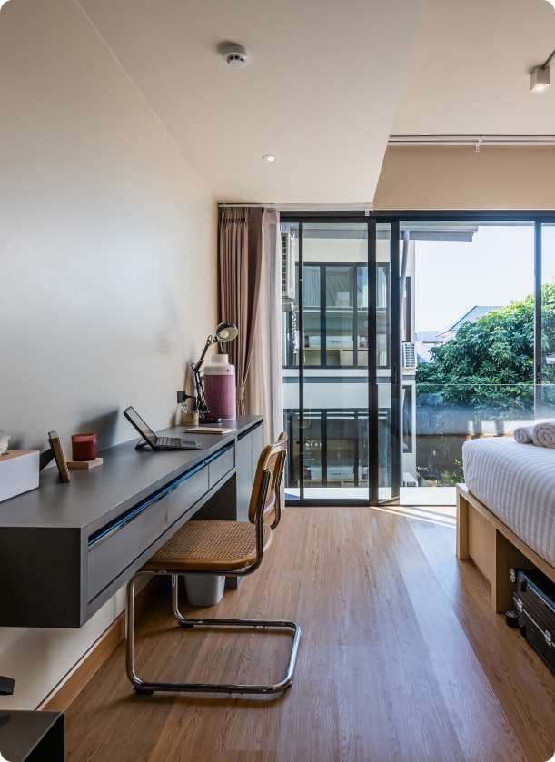 Ensuite Plus room showing desk with laptop, chair, and balcony with garden view