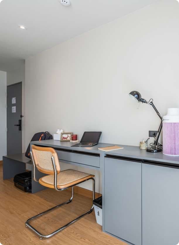 Ensuite Plus room desk area with laptop, lamp, and chair