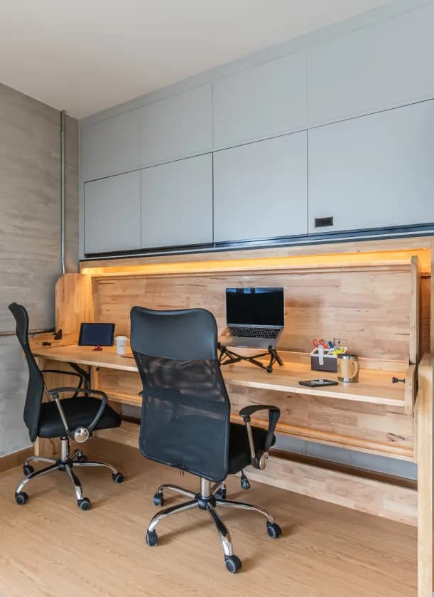 Flexie Plus room with convertible bed folded up as desk with two ergonomic chairs and laptops