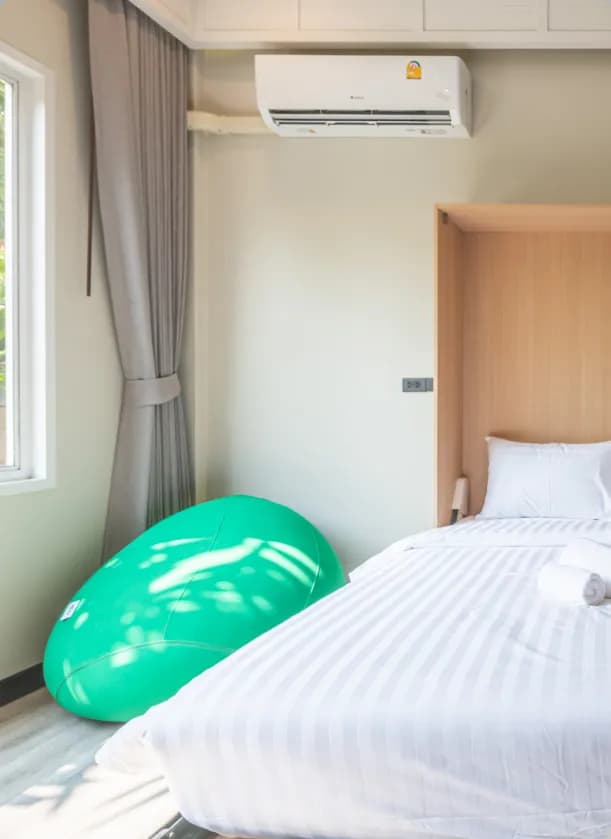 Spacious room with a queen-size fold-up bed, large windows with garden view, air conditioning, and wooden furniture