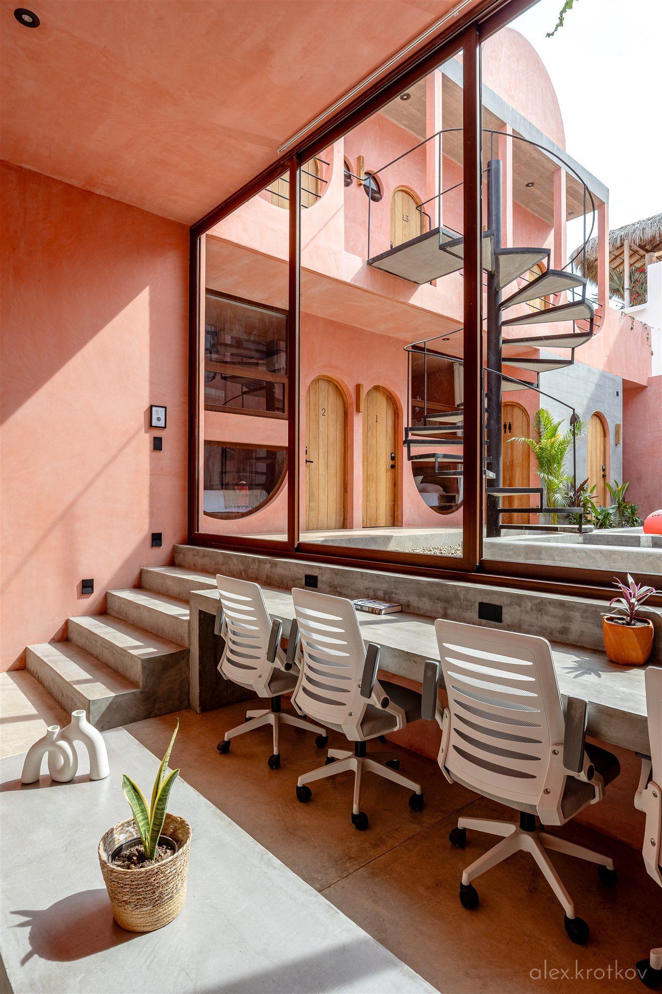 Air-conditioned coworking lounge at Amplitude Coliving, with a long desk, ergonomic chairs, and a large corner sofa — designed for socializing and coworking