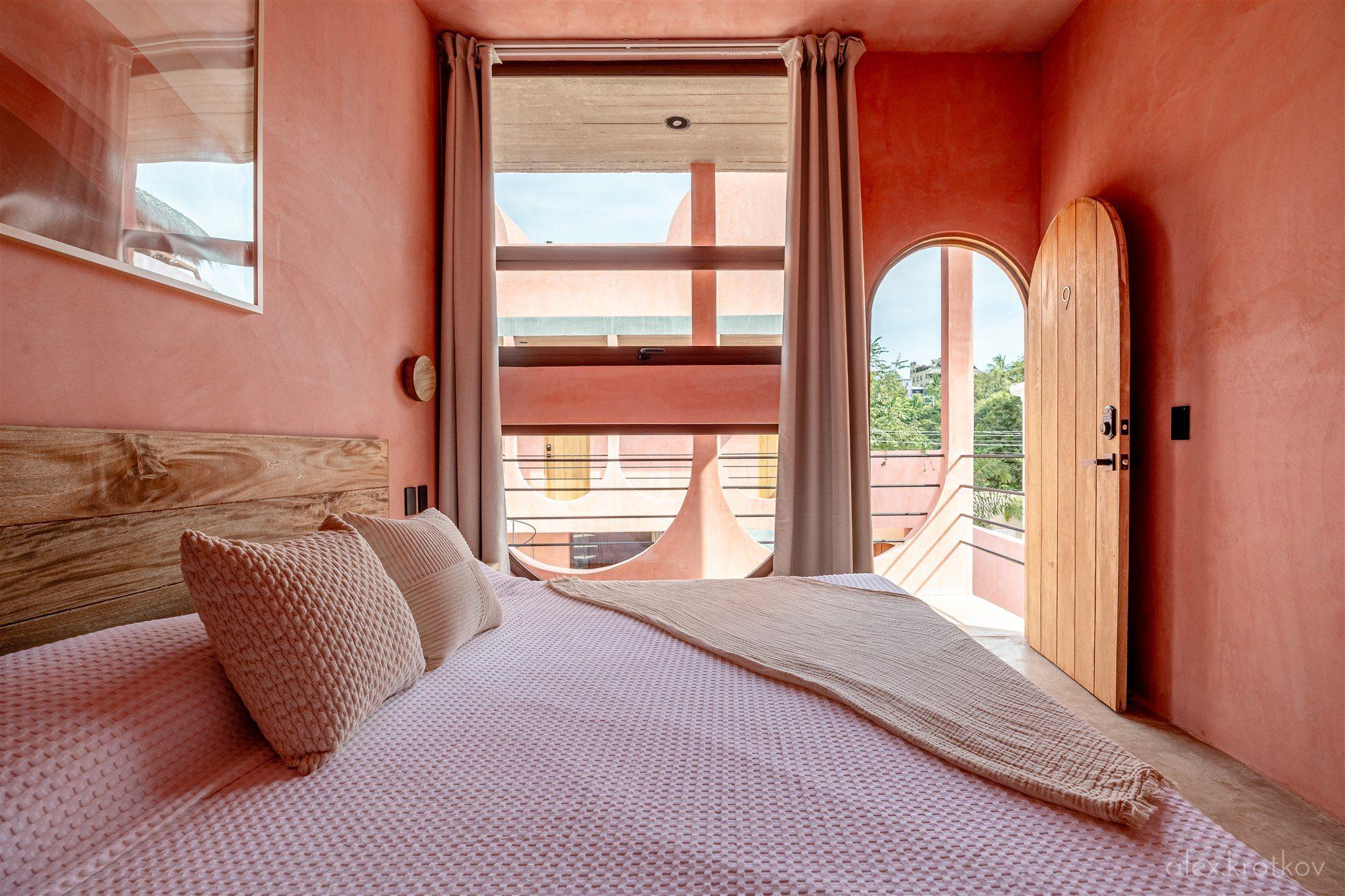Terrace King Room at Amplitude Coliving, featuring a king bed with terrace view overlooking the building's distinctive arched facade