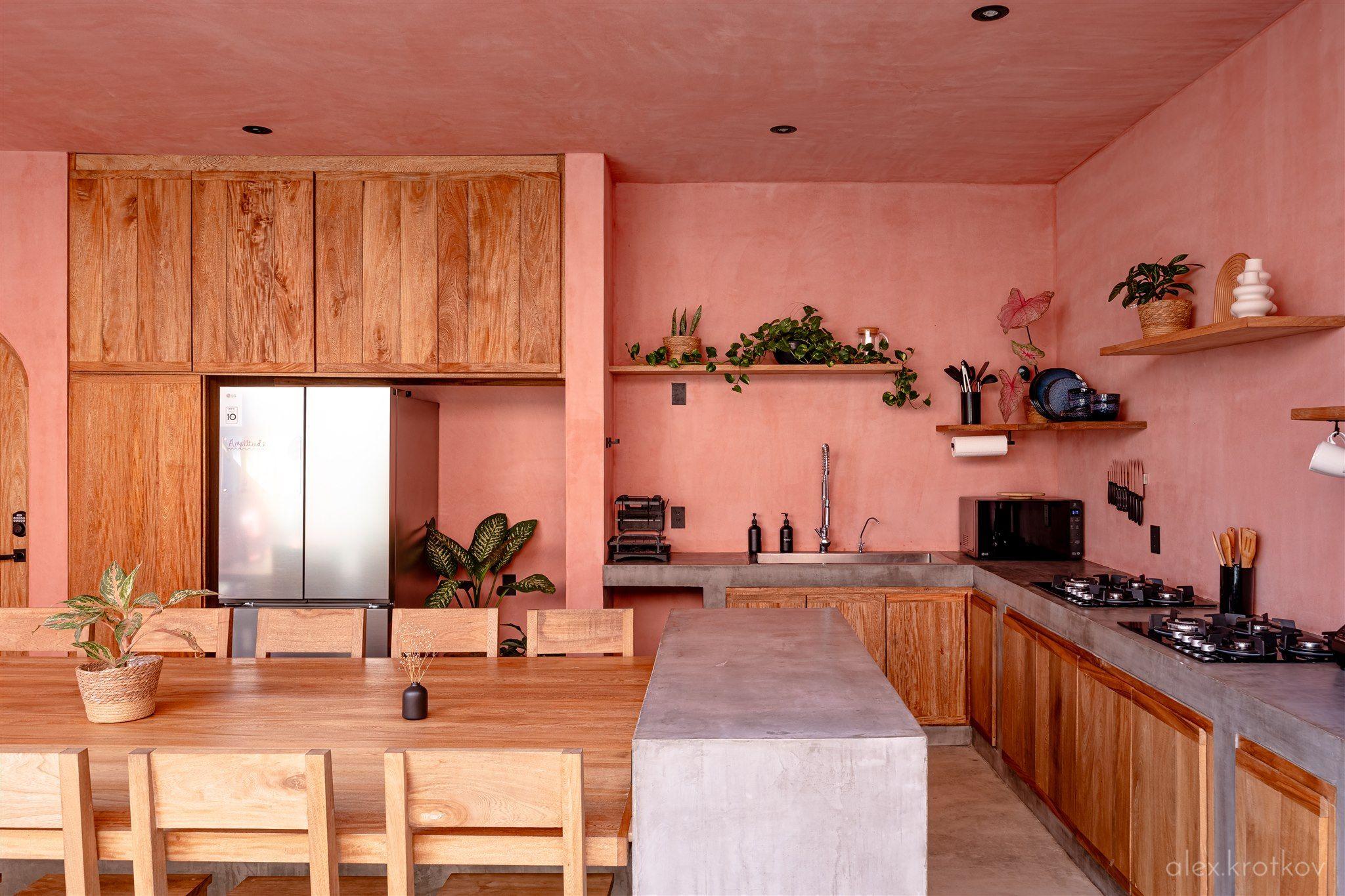 The shared kitchen at Amplitude Coliving, featuring high-end appliances, two 4-burner stove tops, stainless steel cookware, and a large kitchen table for communal meals