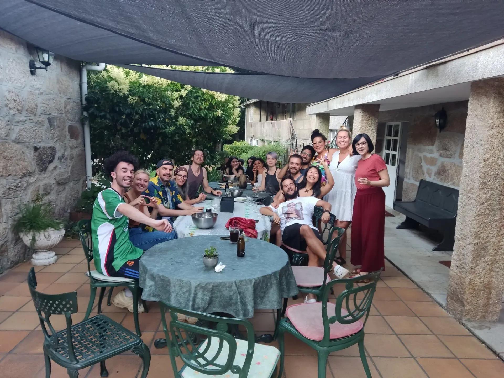 Large group of colivers having dinner together at a round table on the covered patio terrace