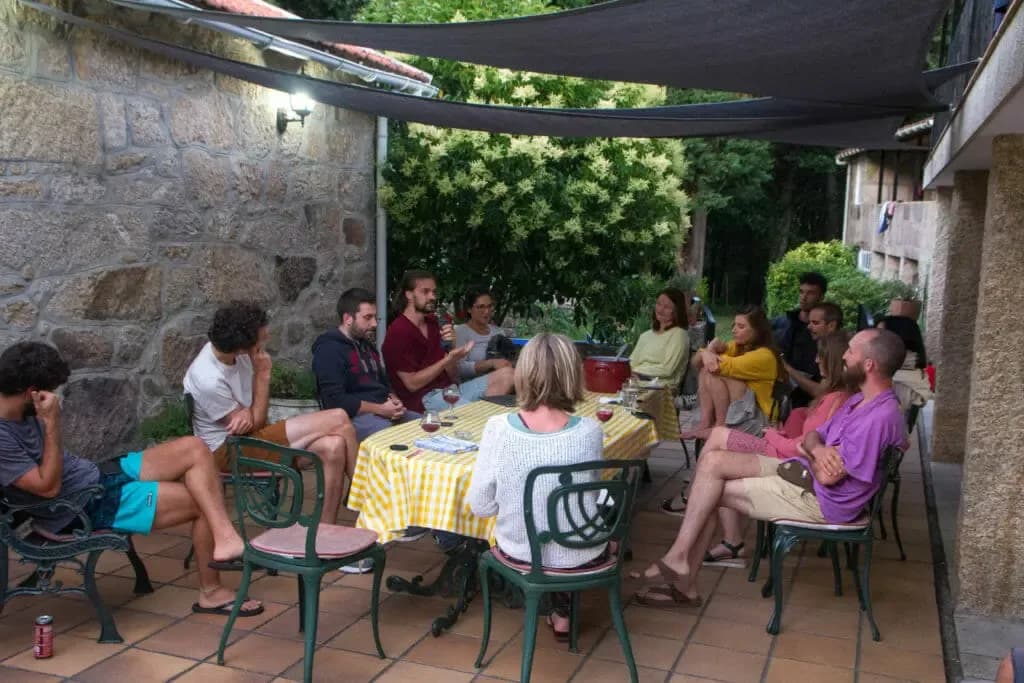Group of colivers seated around a table on the covered terrace, engaged in a sharing session or discussion