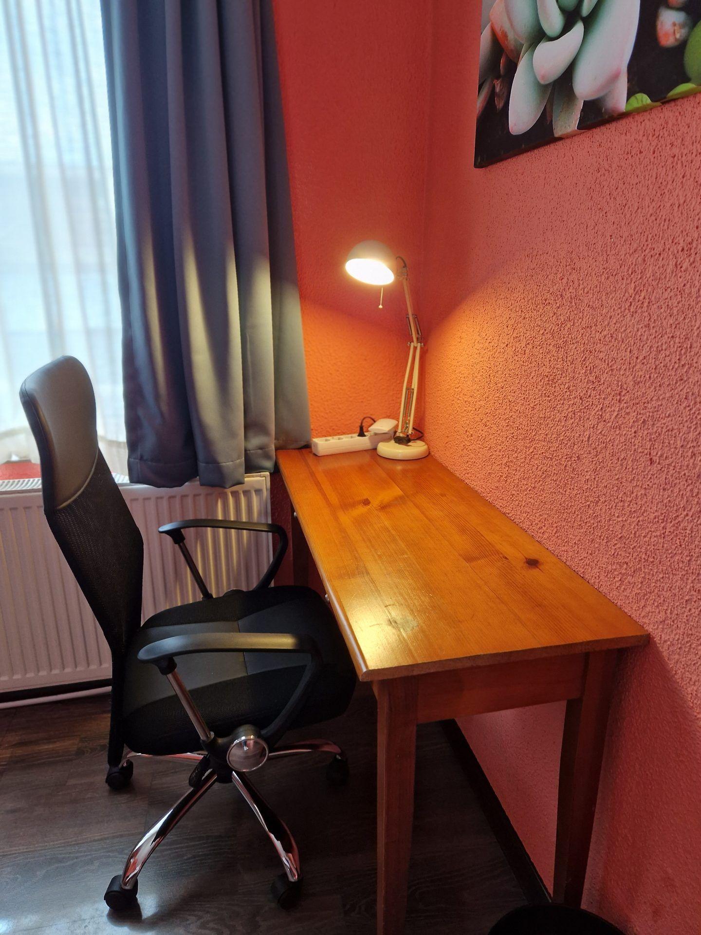 A private room with a wooden desk, office chair, and lamp