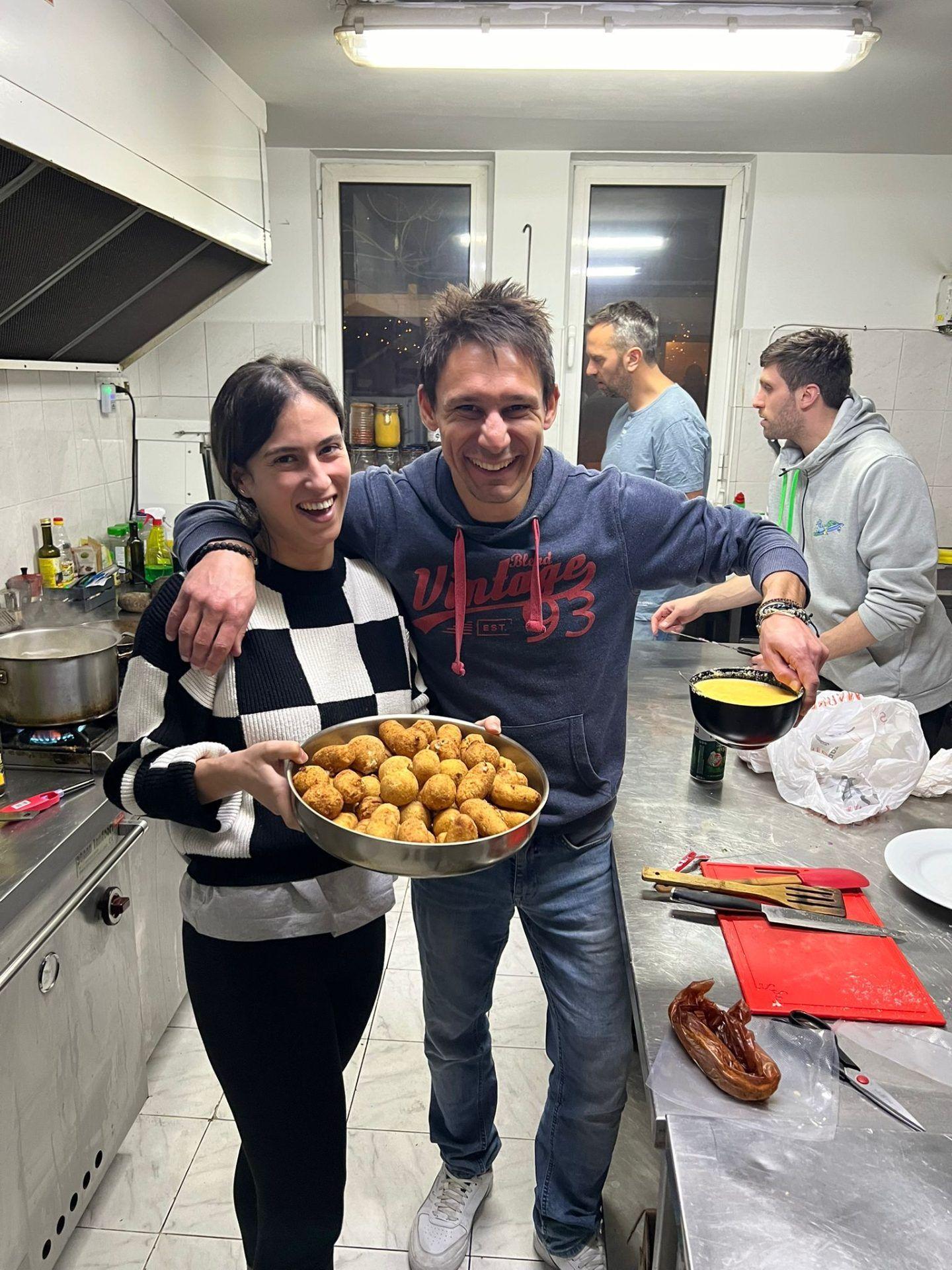 Guests cooking together in the shared commercial kitchen, holding a tray of fried food