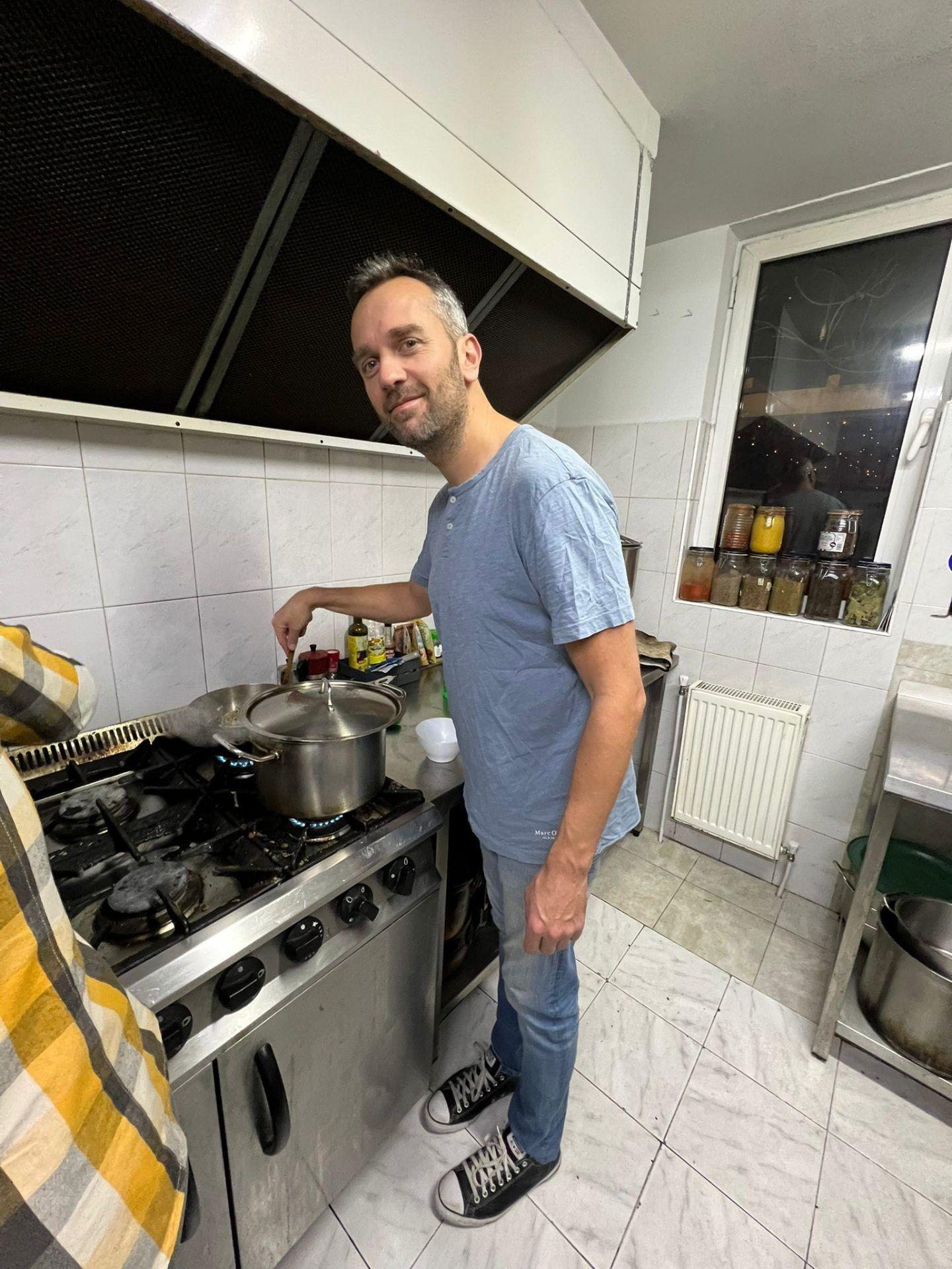 A person cooking at the commercial gas stove in the shared kitchen