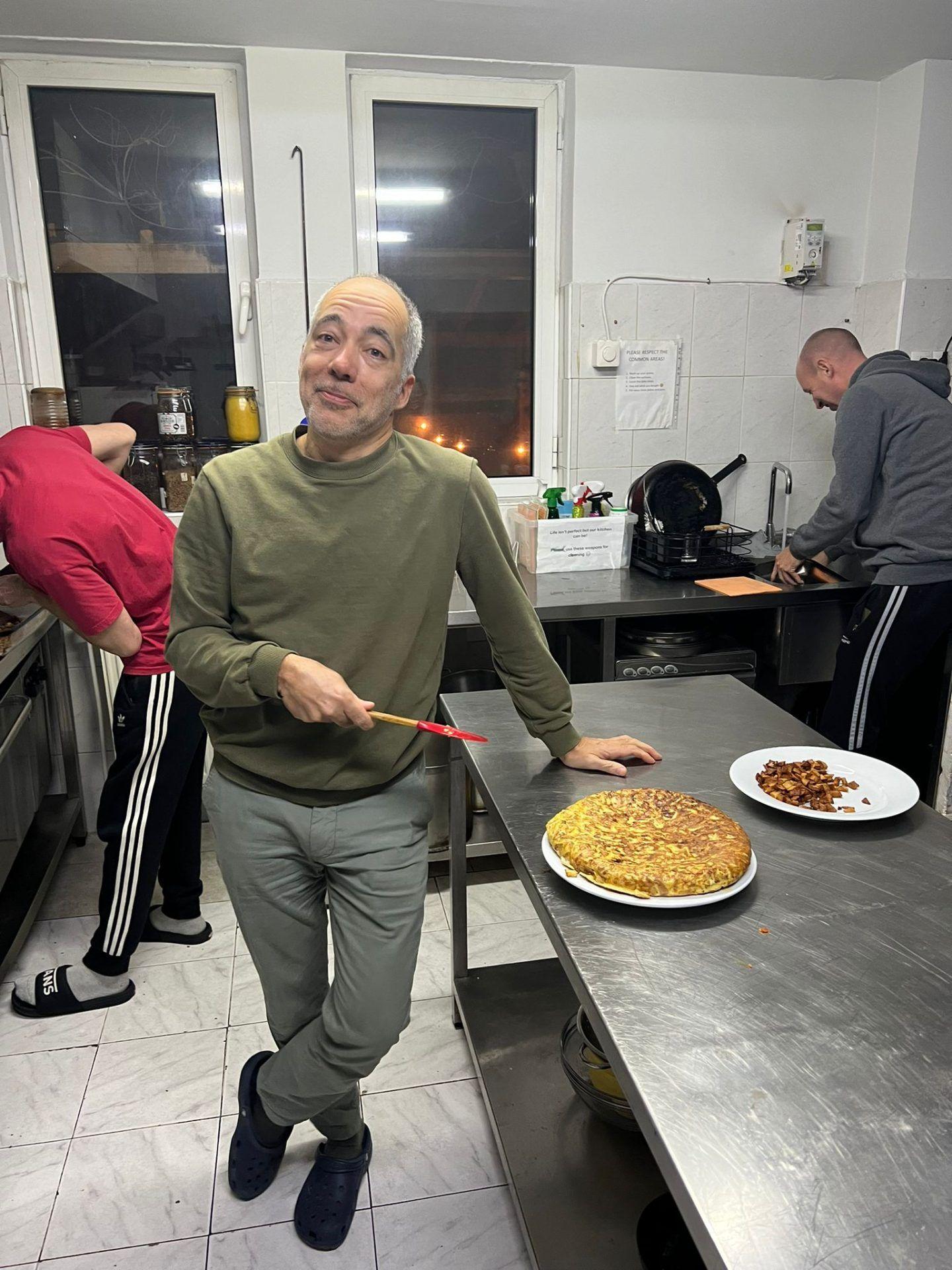 A guest cooking a large omelette in the shared commercial kitchen