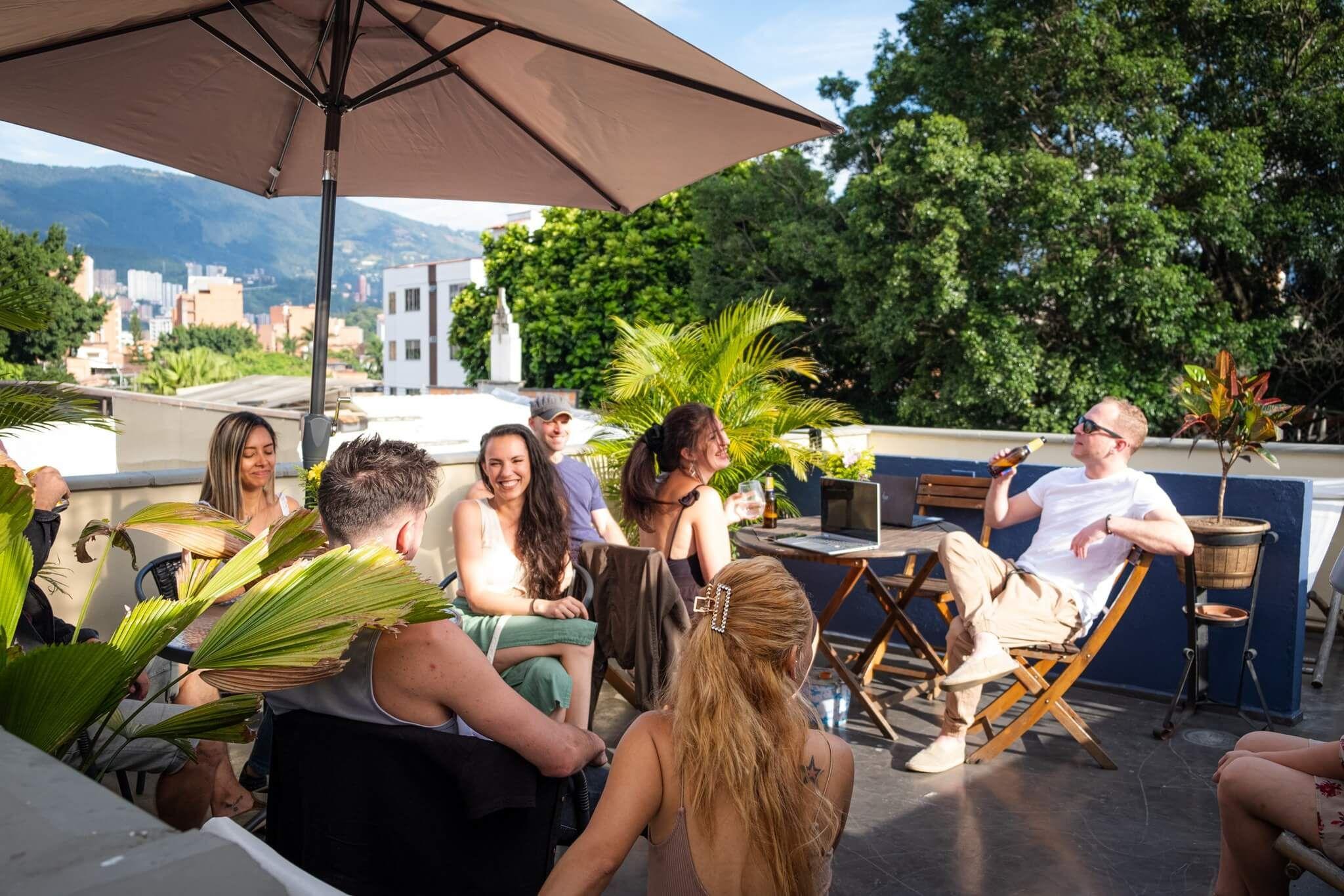 Group of guests socialising on the rooftop terrace with mountain views of Medellín in the background