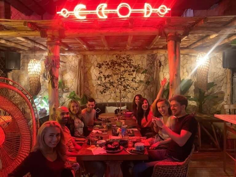 Balu community members enjoying a group dinner at a restaurant with red neon lighting