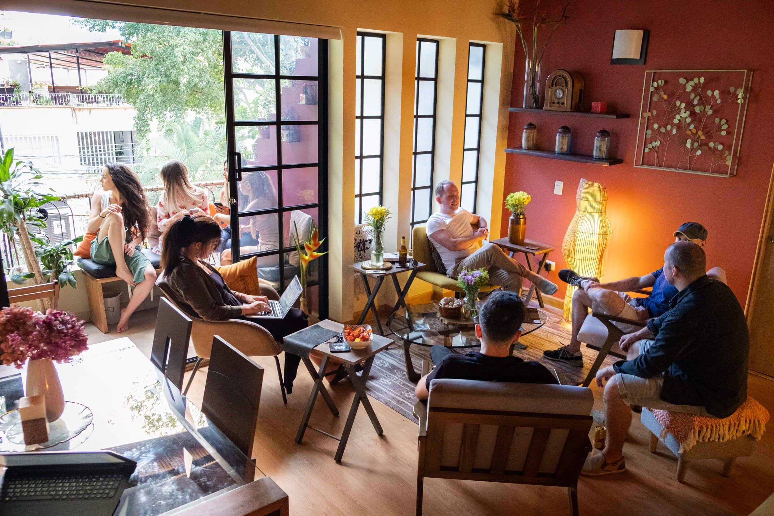 Guests relaxing and working in the living room with open doors leading to the balcony
