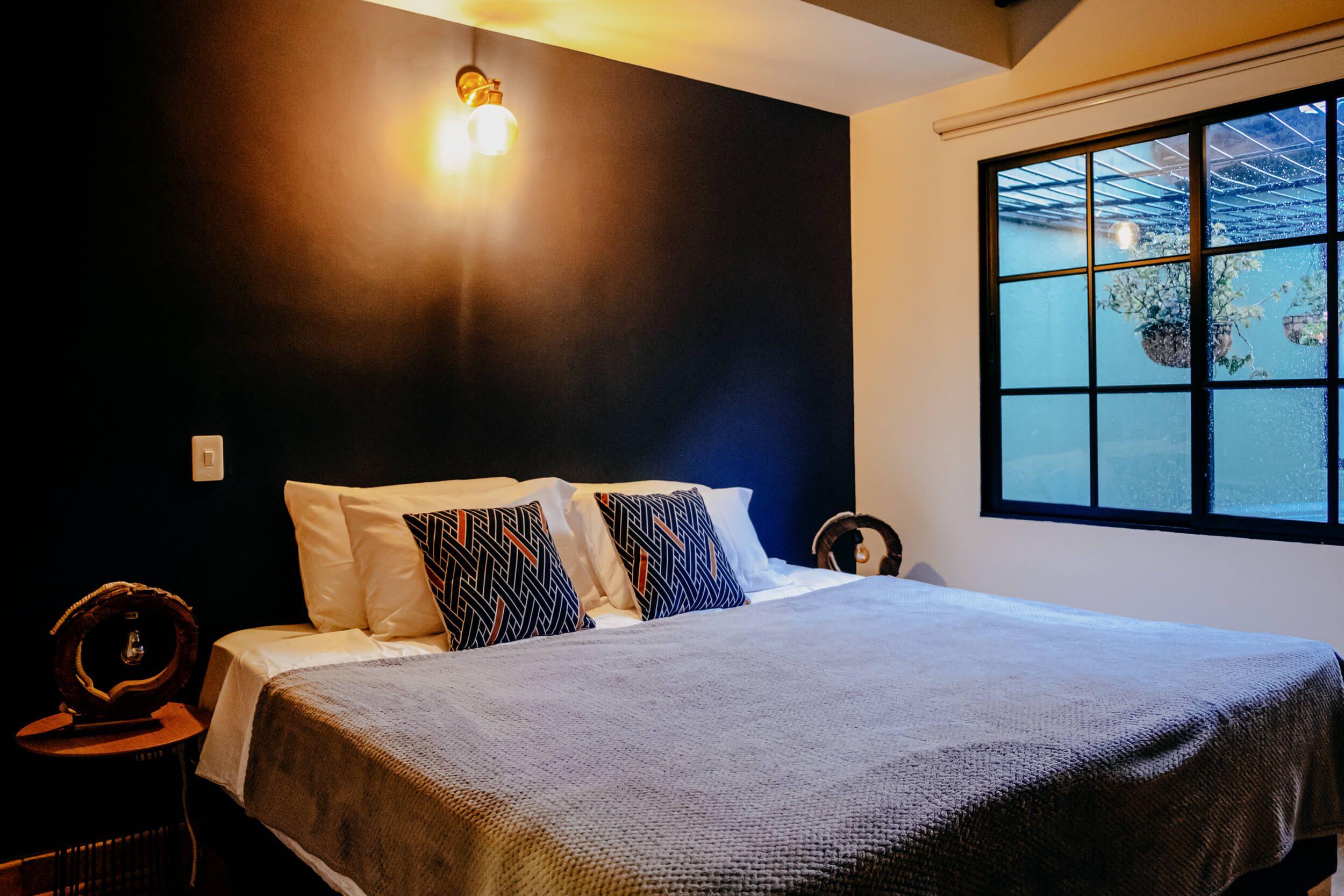 Main view of Bedroom 3 with a huge king bed, large modern windows with hanging plants outside