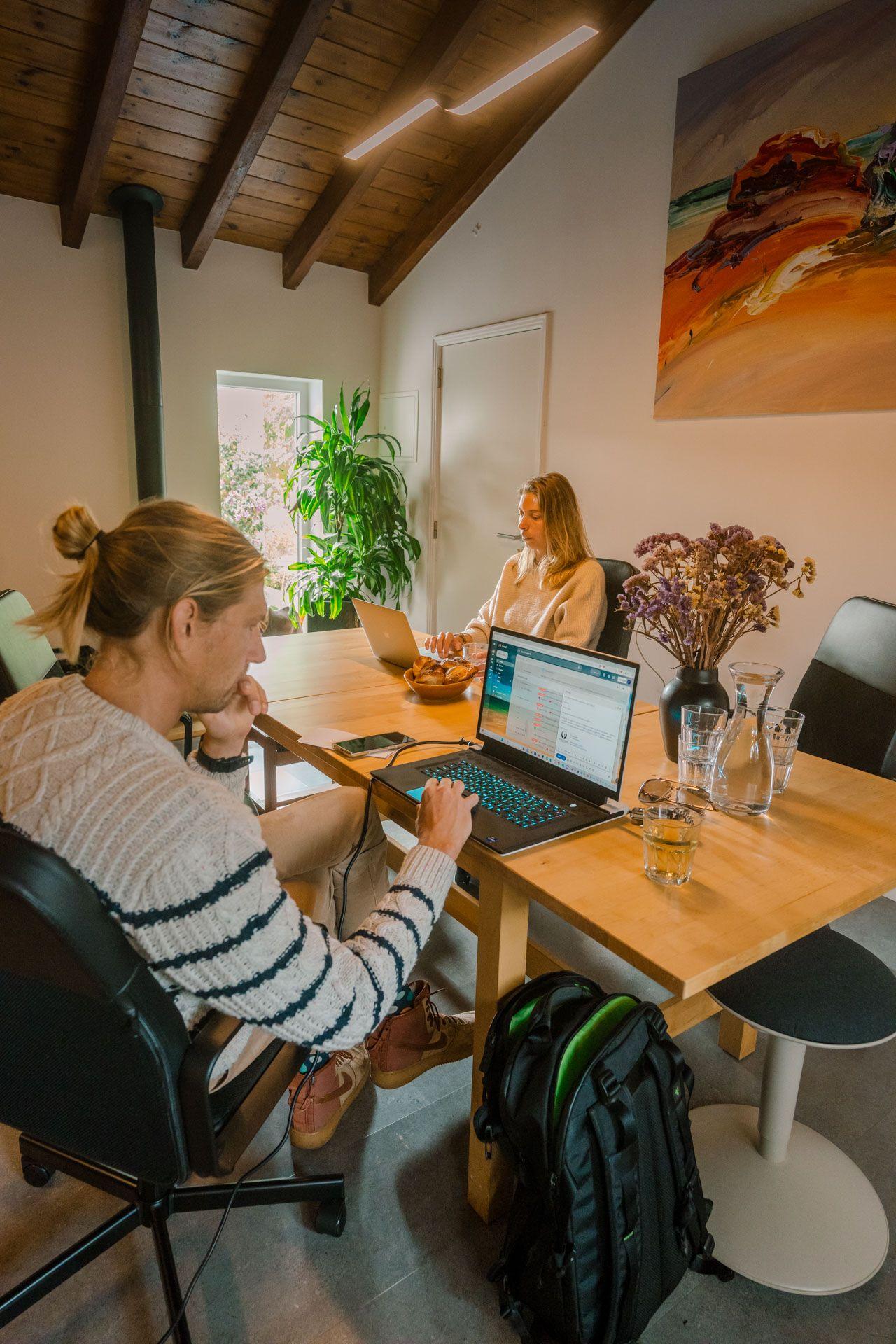 Two guests working on laptops at the communal coworking desks