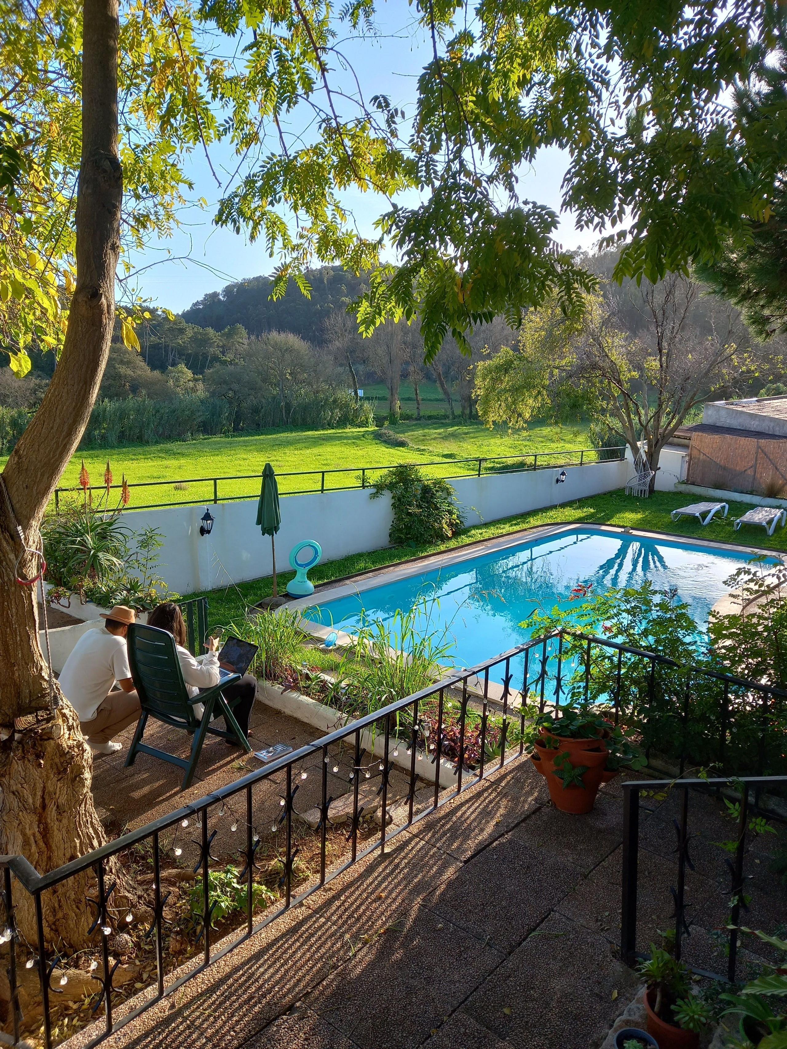 A guest working on a laptop in the garden with pool and valley views