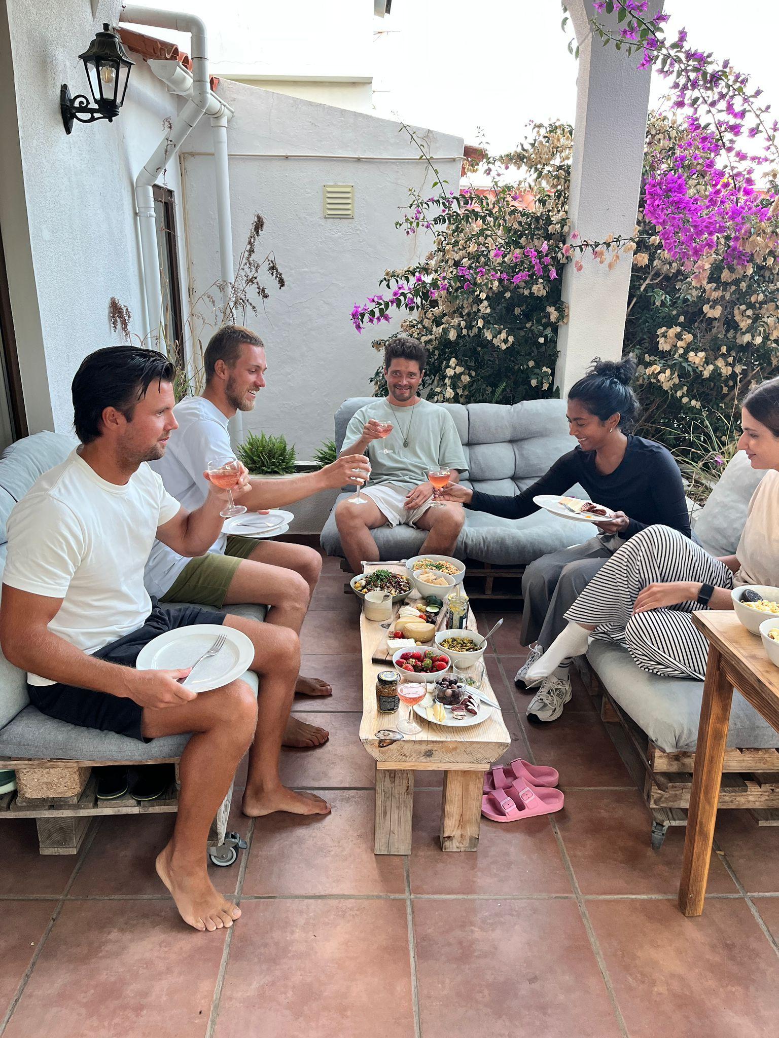 Group of coliving guests sharing drinks and food on the outdoor terrace
