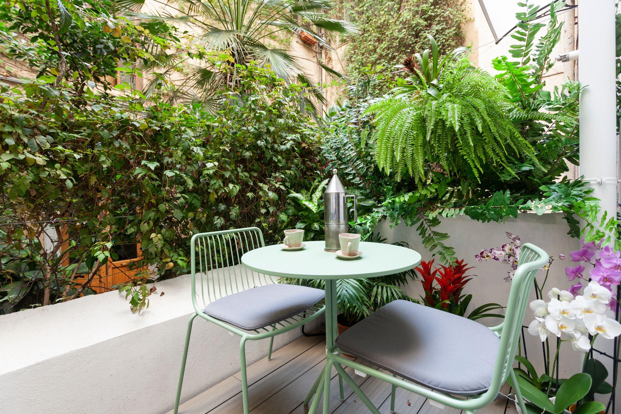 Outdoor garden terrace with green chairs and lush tropical plants at BeetCommunity Agrigento