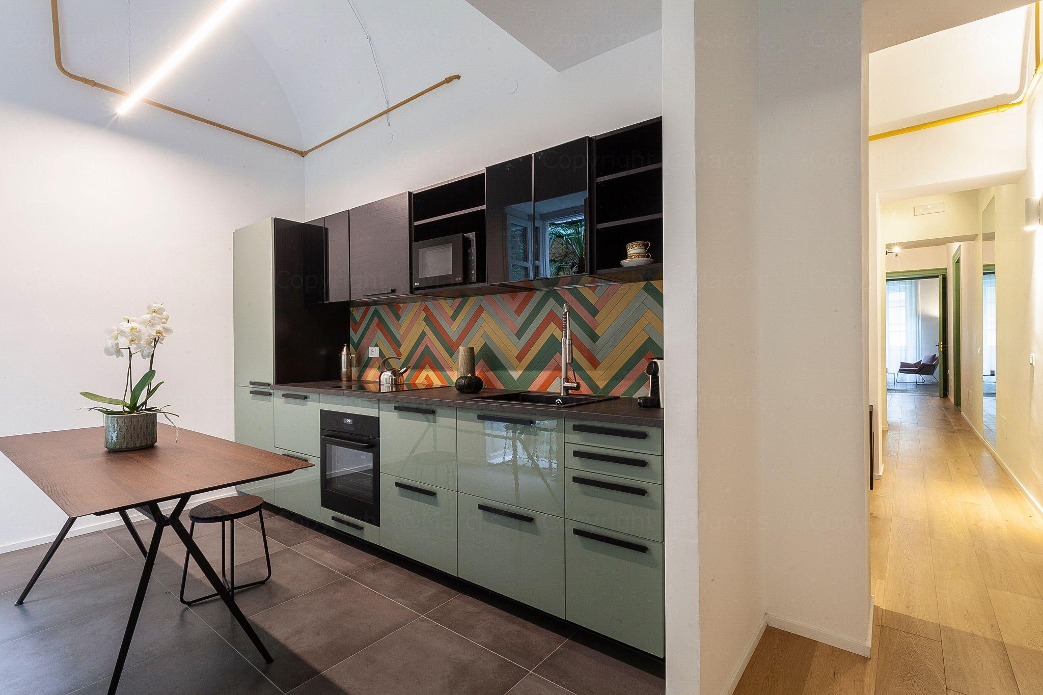 Fully equipped kitchen with green cabinetry and colorful chevron backsplash