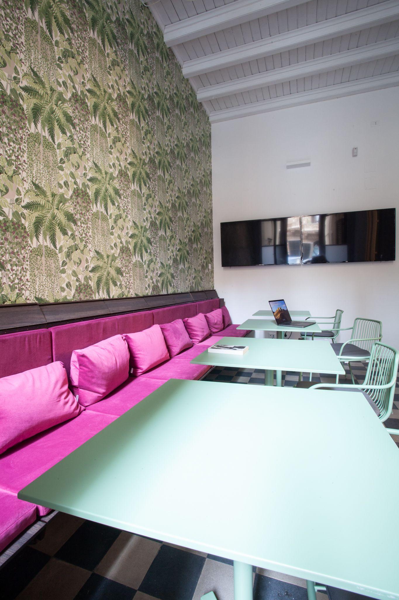 Relaxation area with pink bench seating, mint green tables, and wall-mounted TV