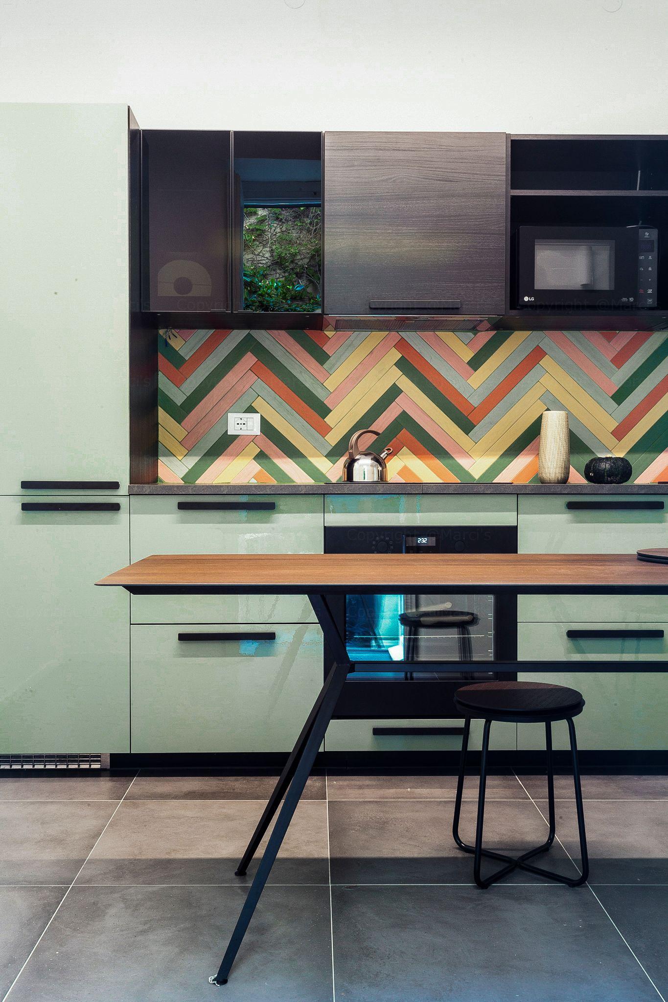 Kitchen with green cabinetry, colorful backsplash, and wooden dining table