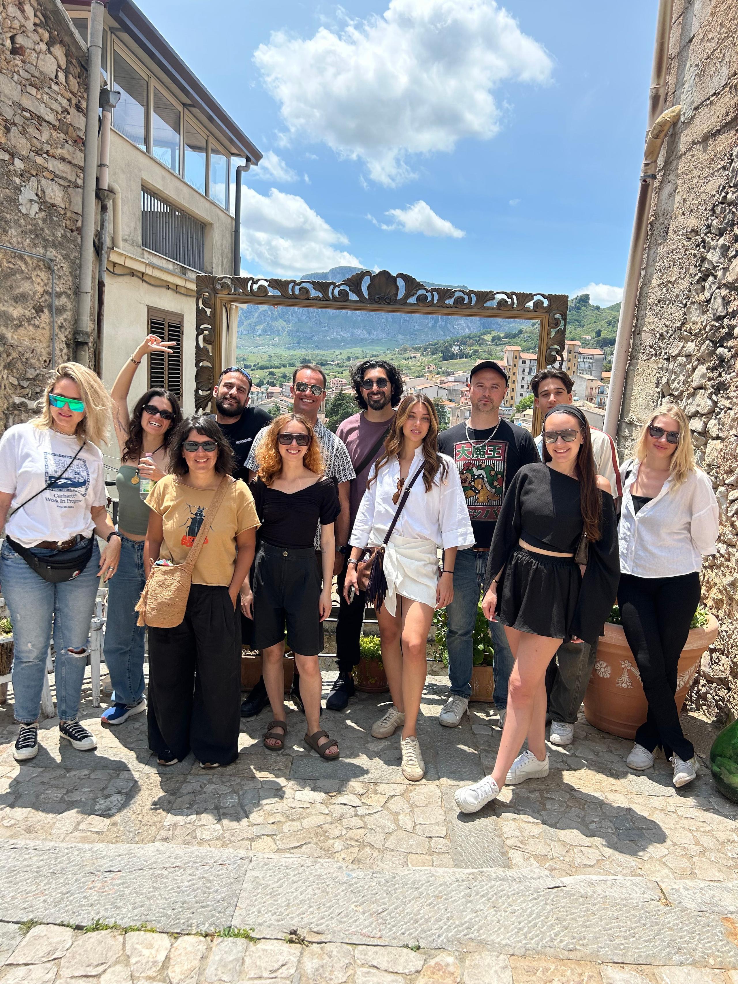 Group of community members posing together outdoors on a Sicilian hillside
