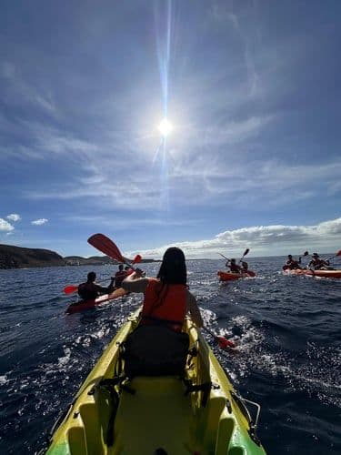 Group of colivers kayaking in the ocean near Tenerife's rocky coastline