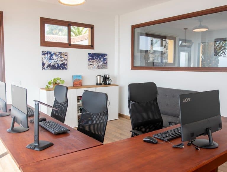 A desk with computers and monitors in Bencomo Coliving coworking