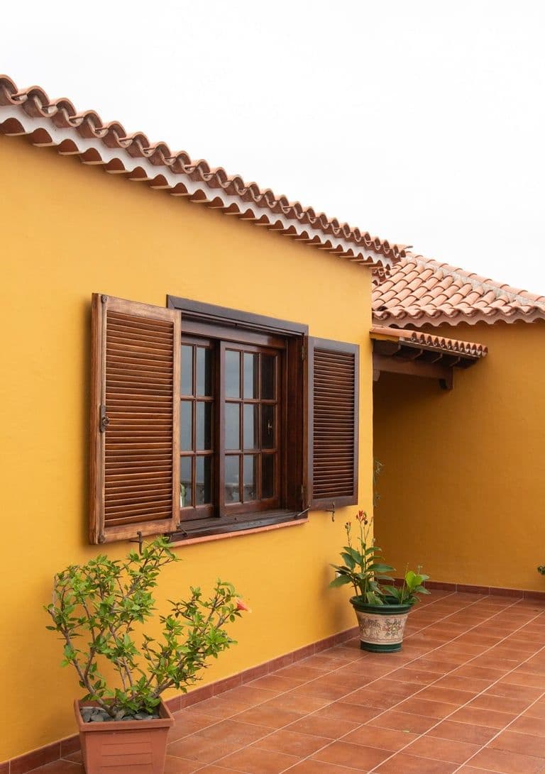 House with yellow walls and wooden windows — exterior facade of Bencomo Coliving in Santa Úrsula, Tenerife