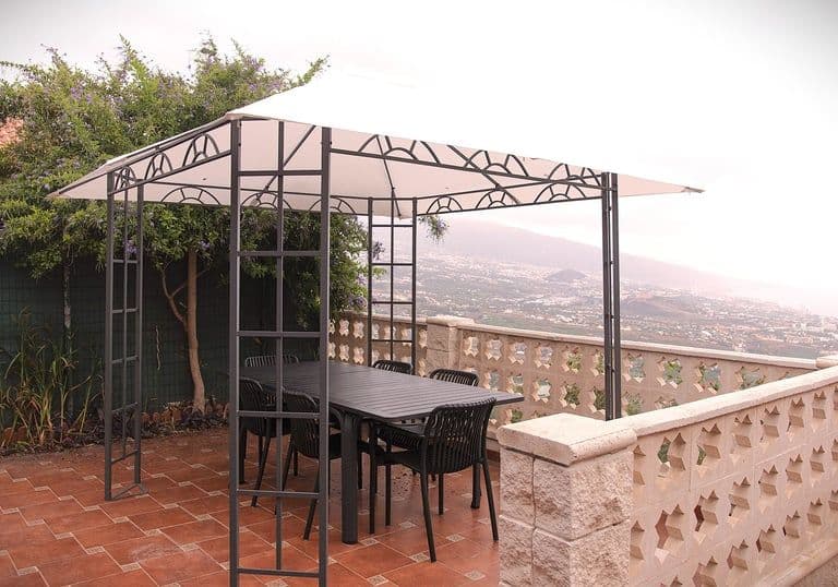 Table with chairs in a covered outdoor area overlooking the city, sea and mountains