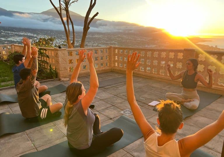 Colivers doing yoga on the outdoor terrace at sunset with panoramic views of the valley and ocean