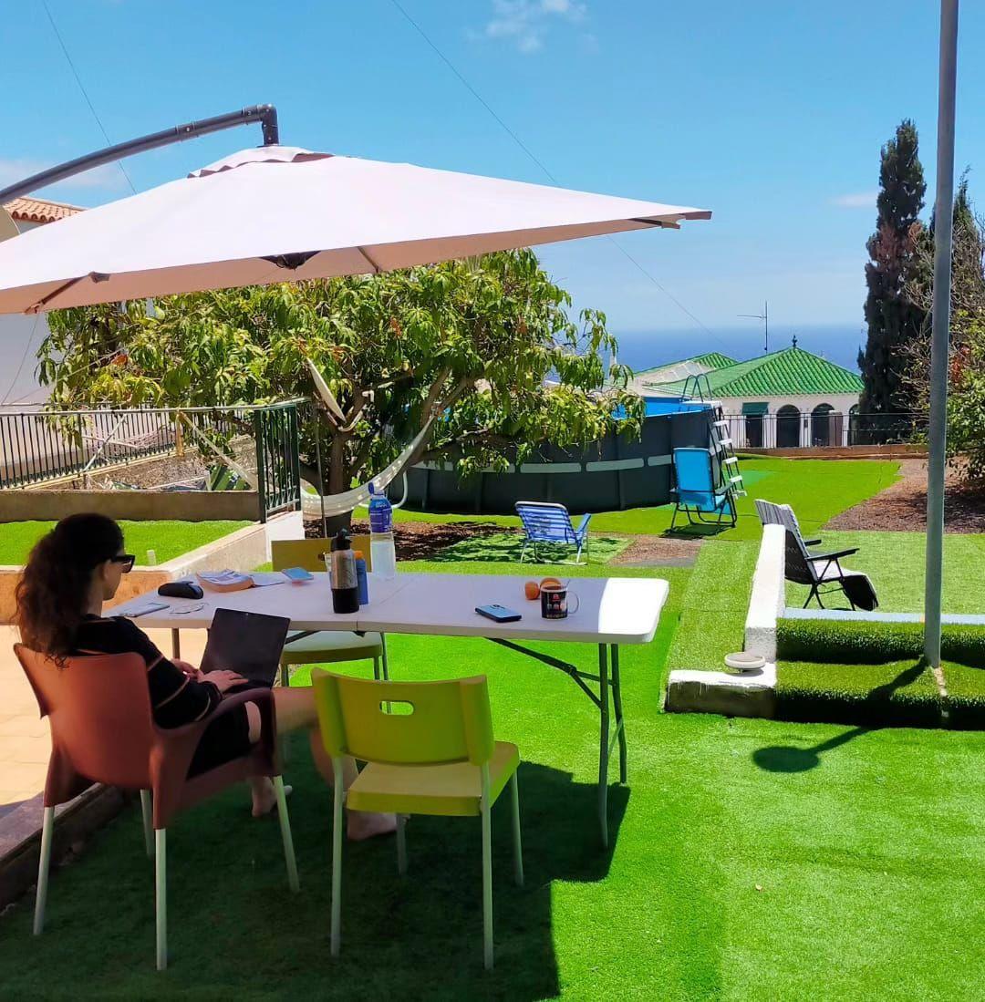 Person working on laptop at outdoor table in the garden with sea views