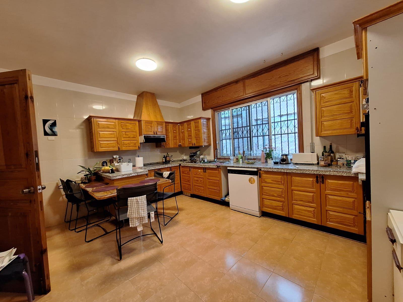 Fully equipped shared kitchen with wooden cabinets and dining area