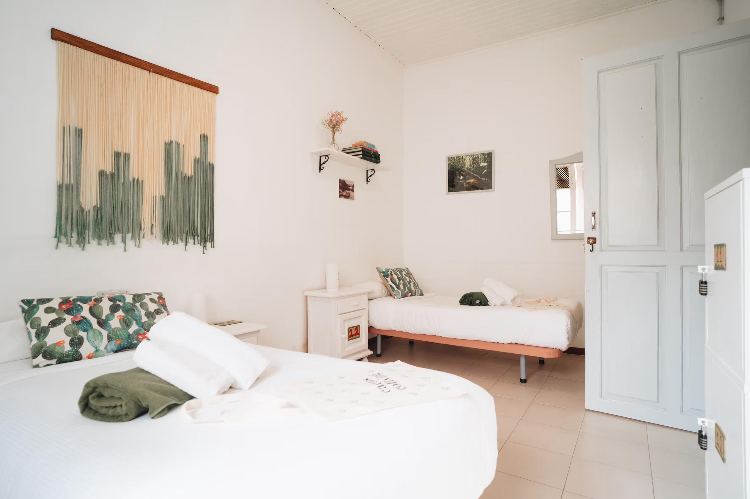 Double room with two single beds, cactus-themed pillows and window at Cactus La Gomera
