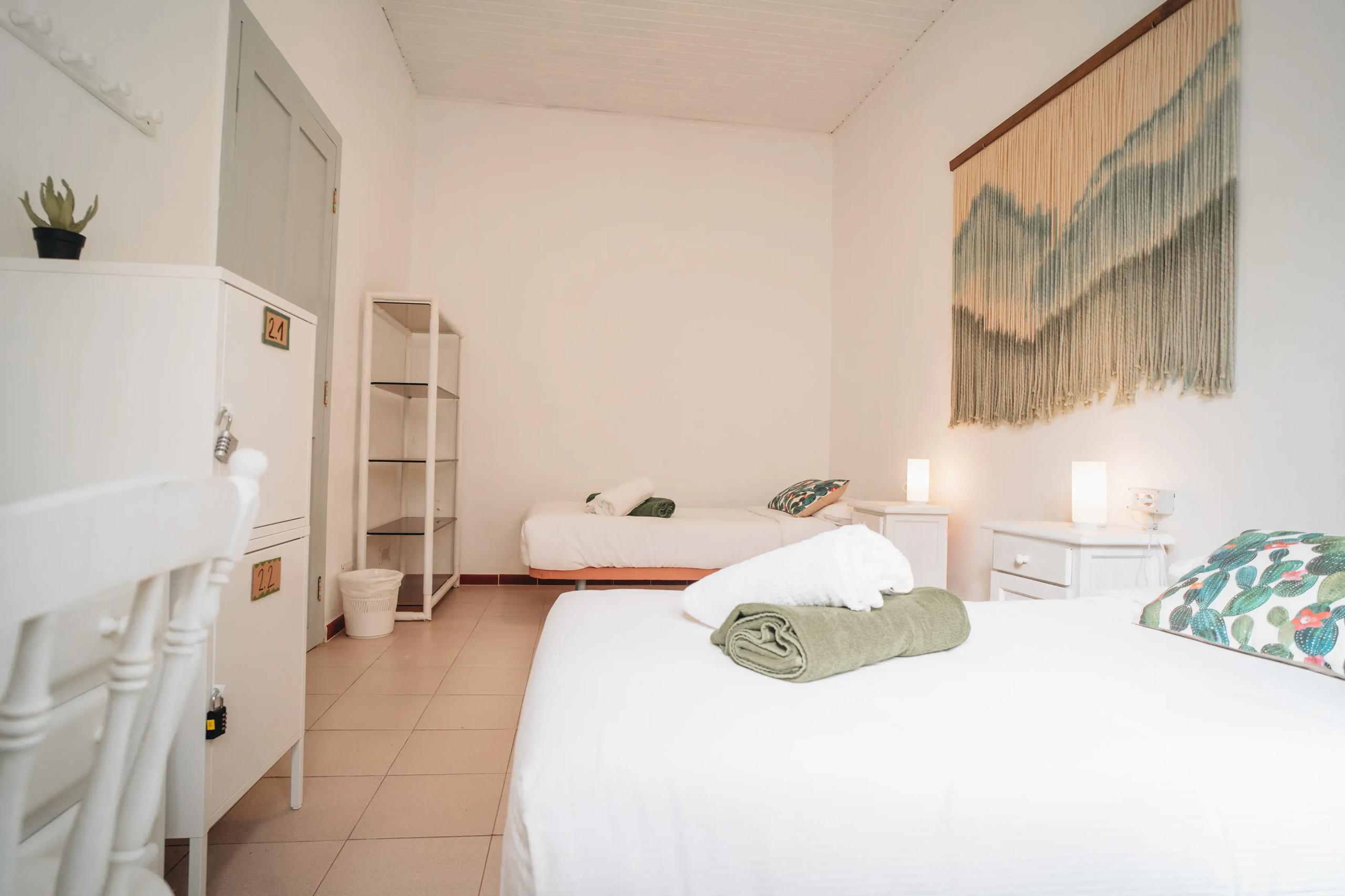 Shared room with two individual beds and macramé wall art at Cactus La Gomera