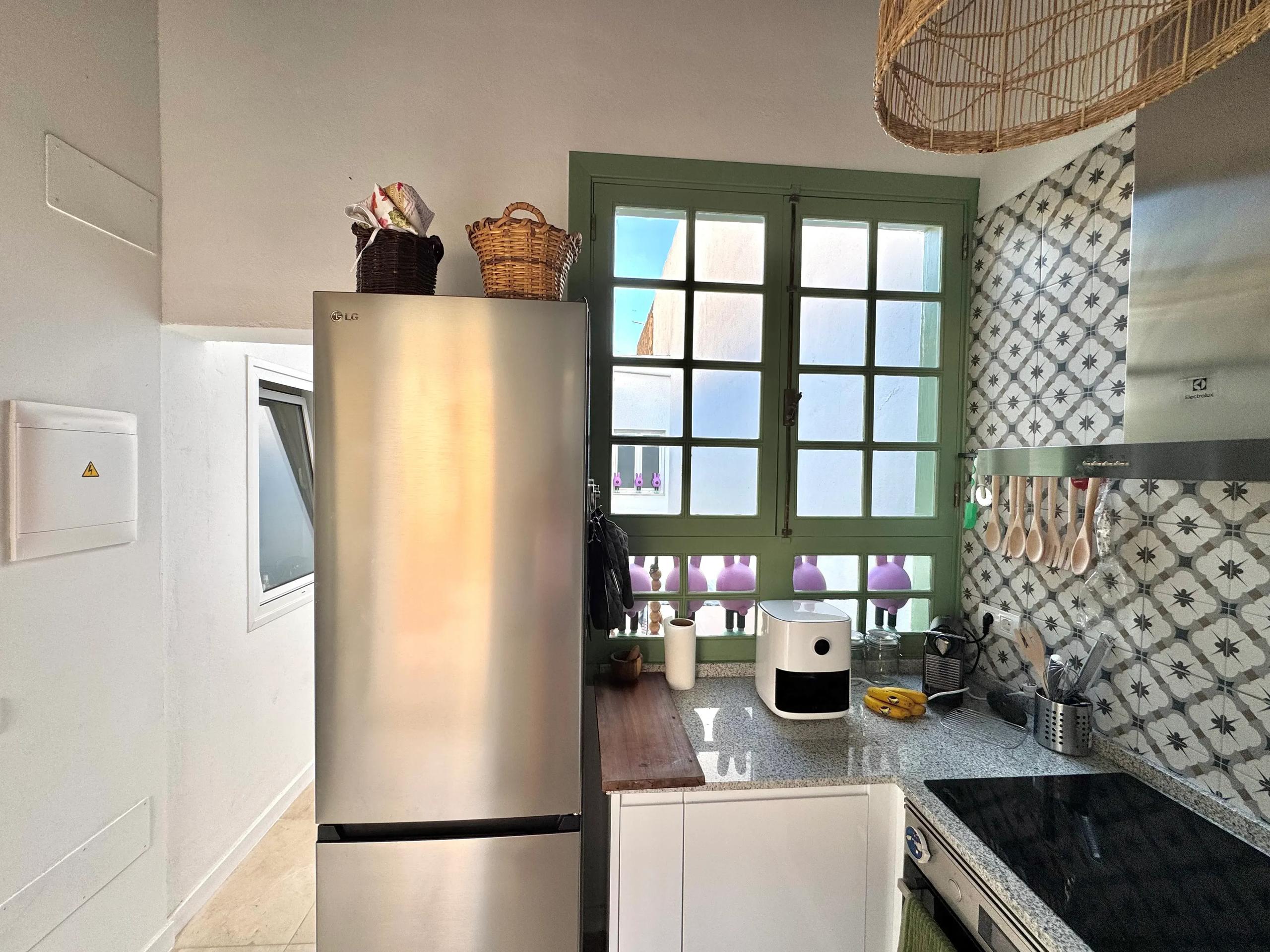 Shared kitchen with stainless steel fridge, patterned tile backsplash and traditional green-framed window