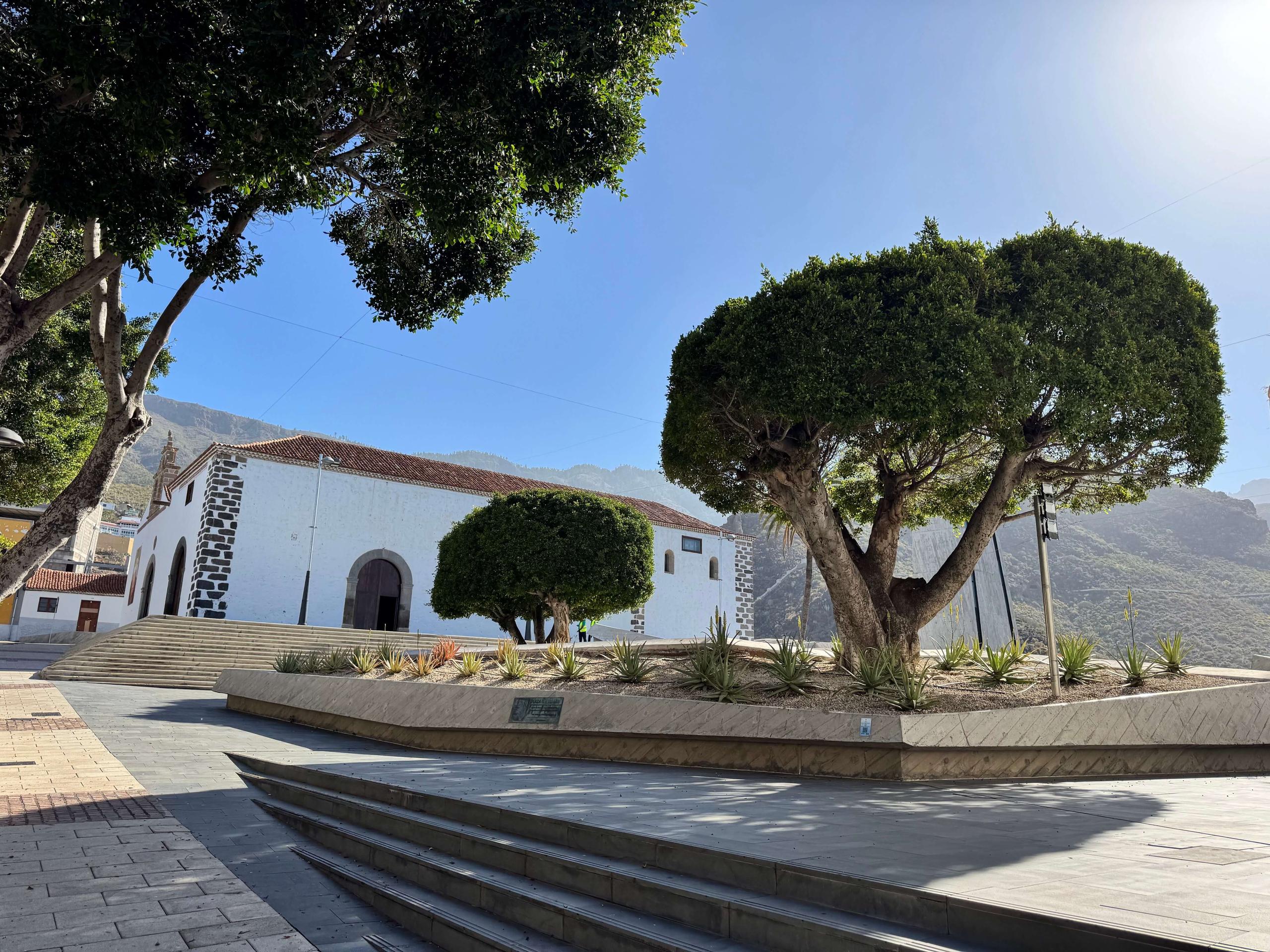 Adeje town square with a traditional white church, manicured trees and mountain backdrop