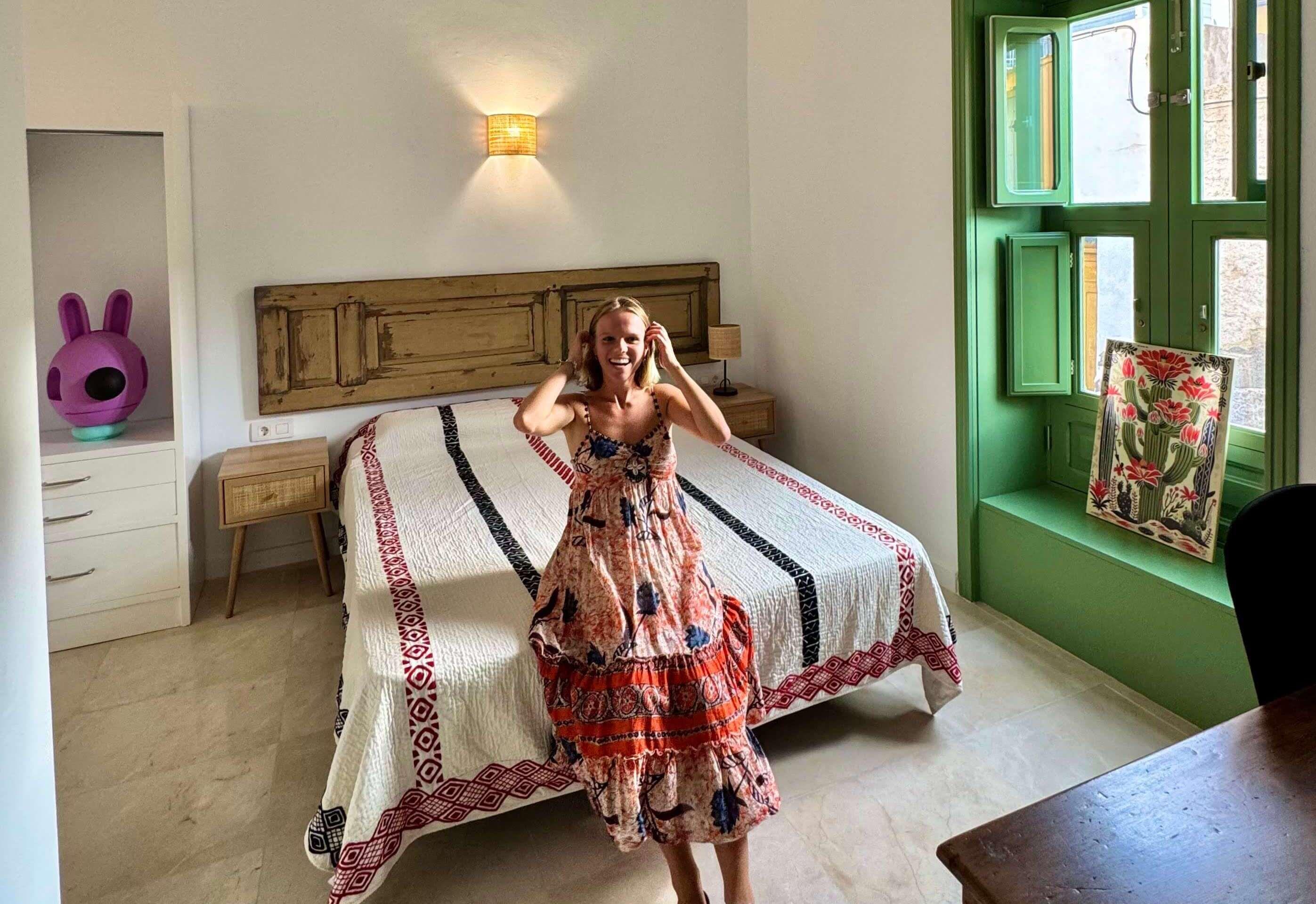 Spacious double bedroom with wooden bed, green-framed window and wooden desk — one of the rooms in the Adeje coliving