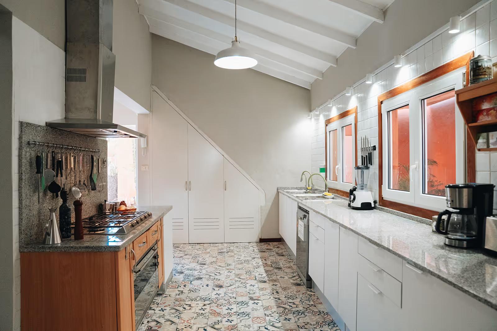 Wide-angle view of the fully equipped indoor kitchen with stove, countertops, and patterned tile floor