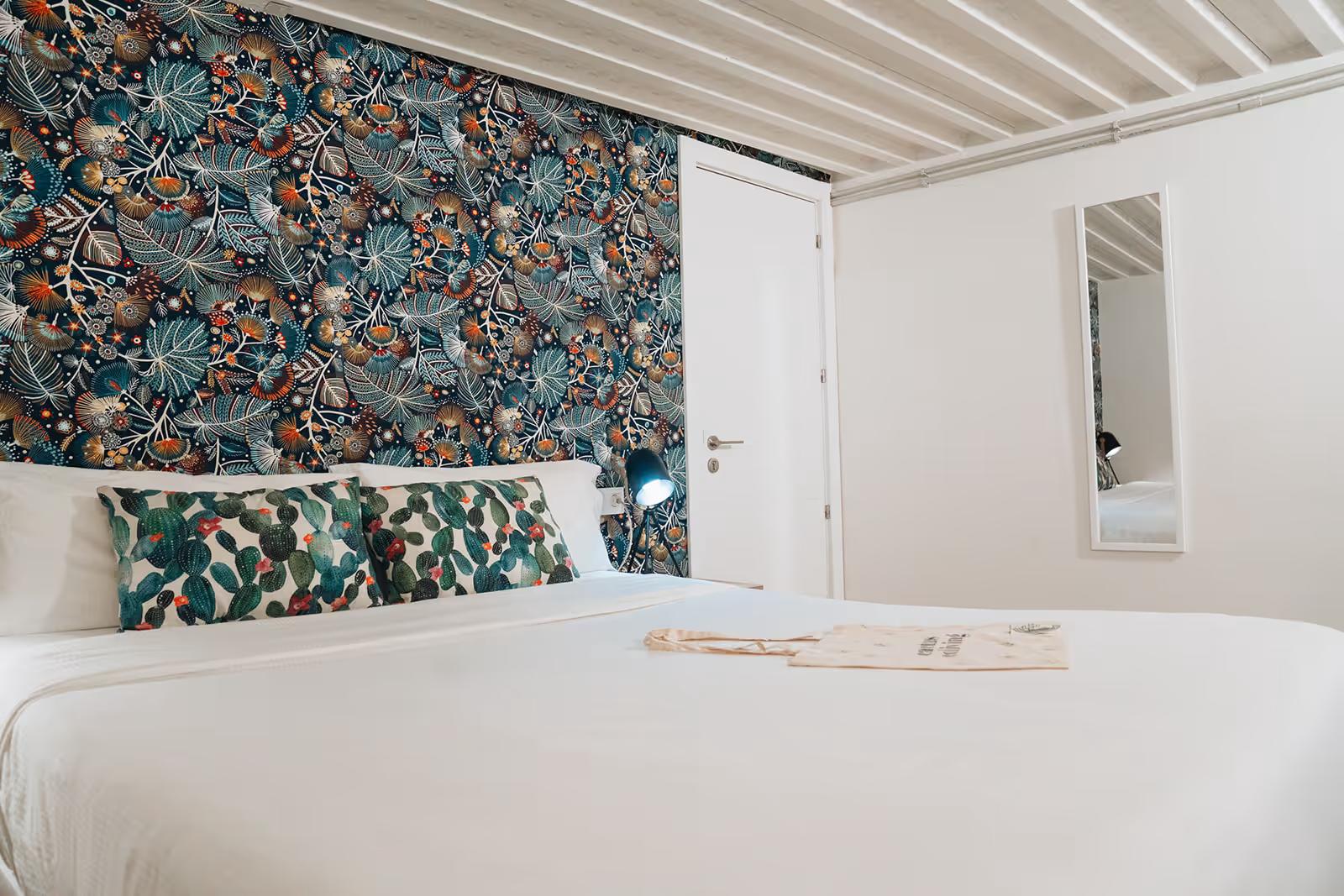 Premium double room with decorative botanical wallpaper headboard and cactus-print pillows