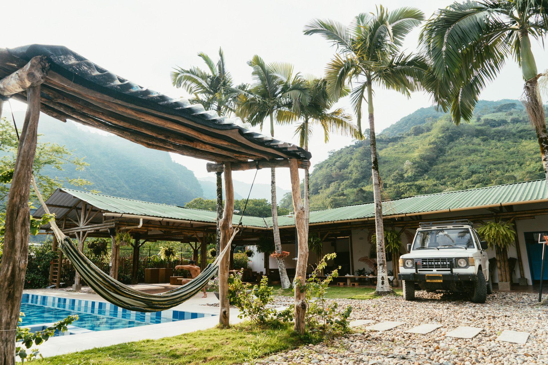 Exterior view of Casa Kandamy showing the swimming pool, hammock, palm trees, and mountain backdrop