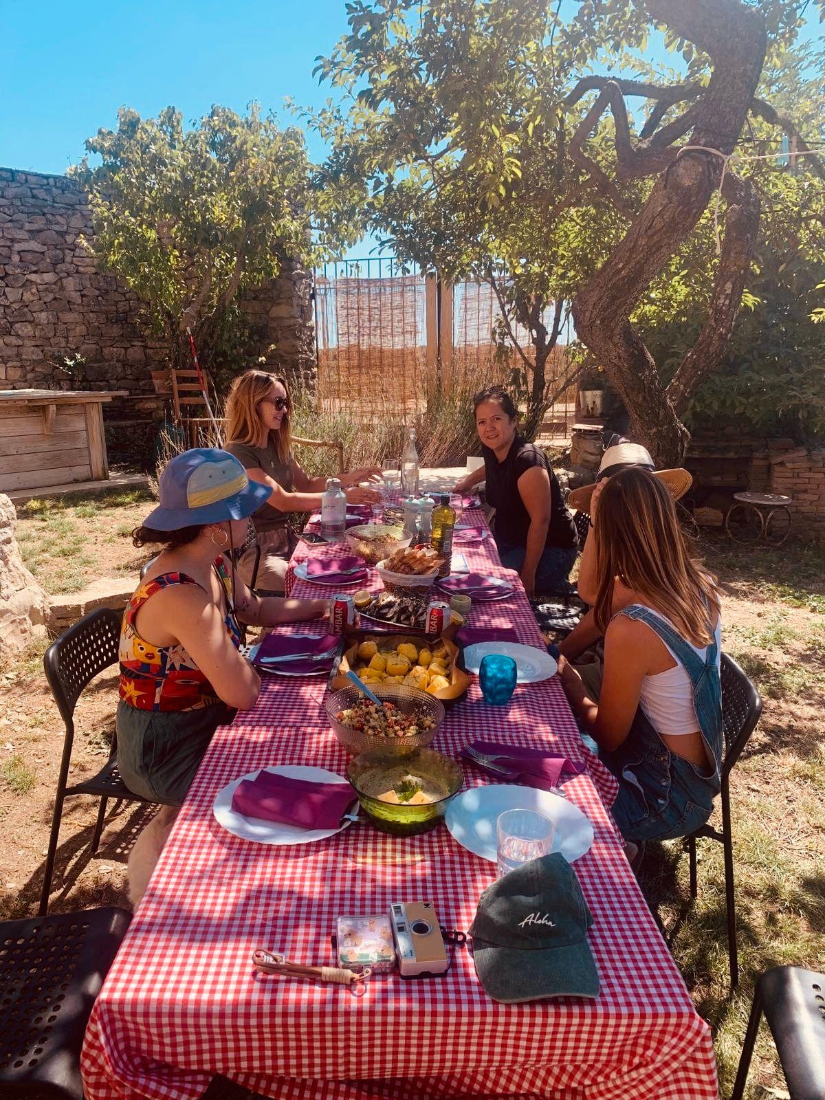 Guests enjoying a shared outdoor meal at a table under the trees in the garden