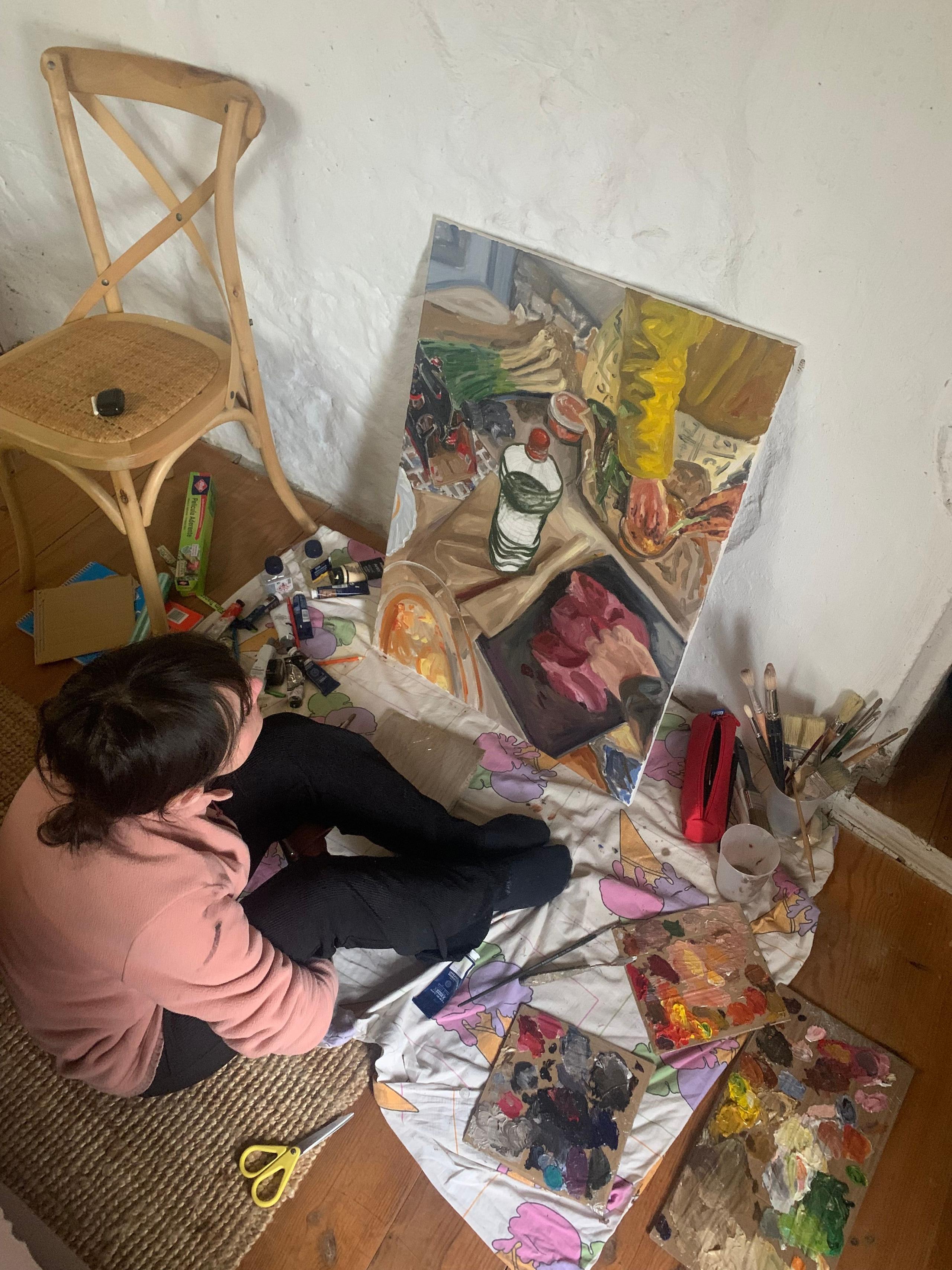 Artist Elena Prada working on a painting on the floor during the art residency at Casa Pardal