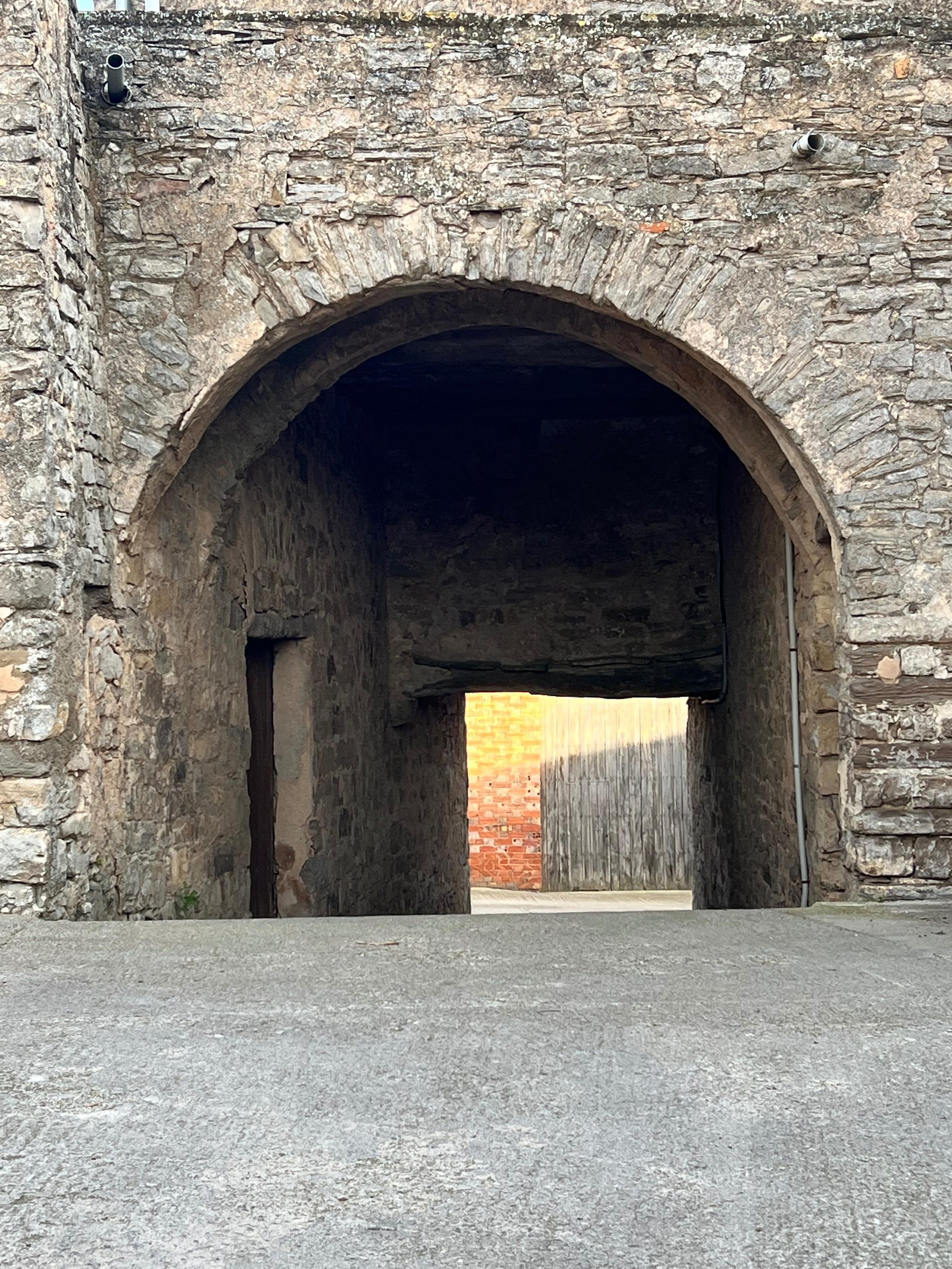 Stone archway entrance at Casa Pardal with golden light visible through the passage