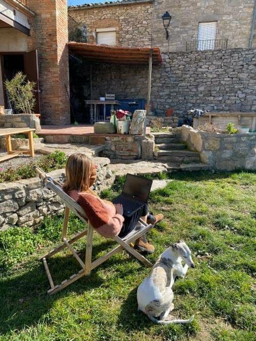 The garden at Casa Pardal — a person working on a laptop in a deck chair with the dog nearby