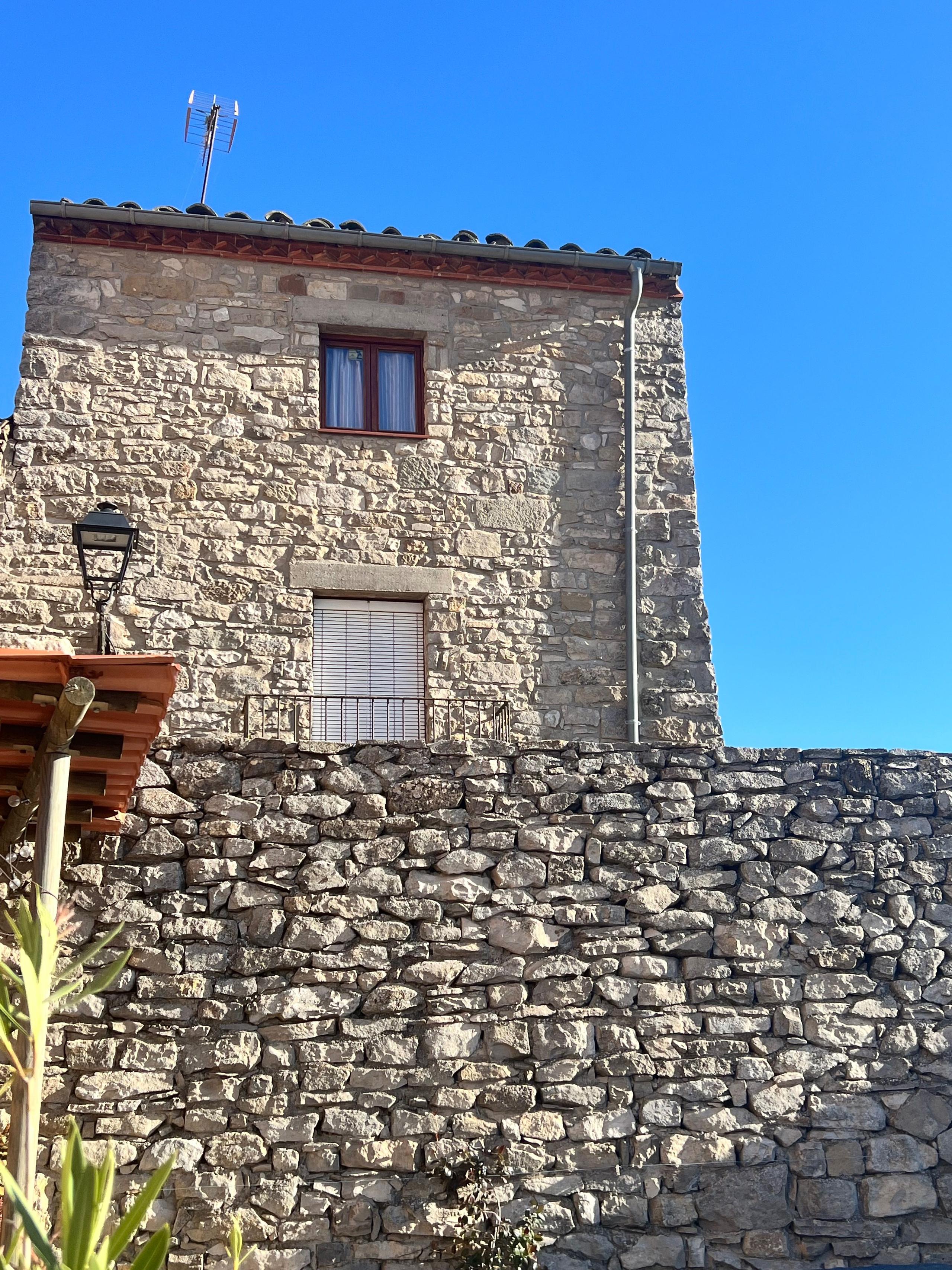 Stone facade of Casa Pardal against a bright blue sky, showcasing the rustic architecture