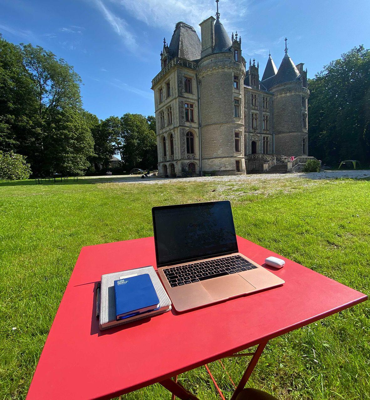 Laptop on a red table in the park with the château in the background