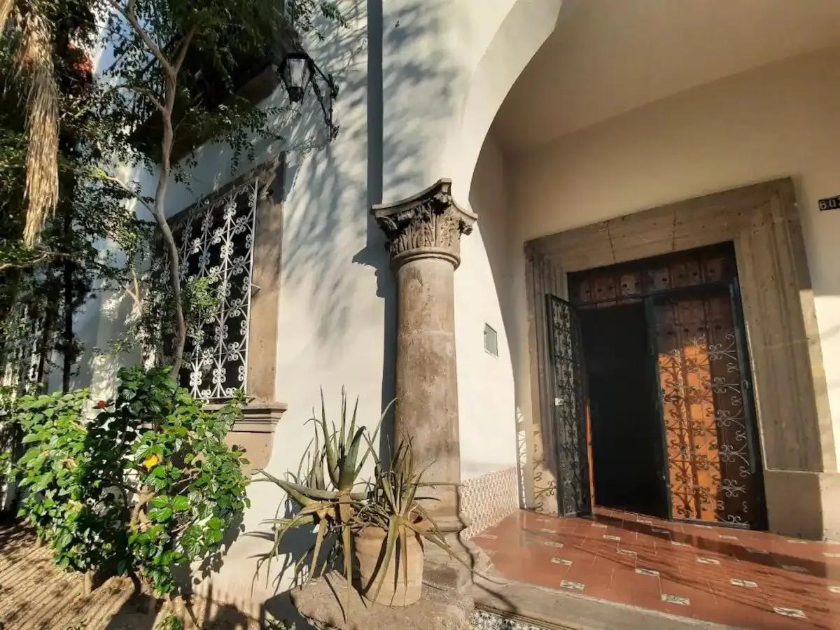 Front entrance of the coliving building with a stone column, arched doorway, iron gate and potted plants